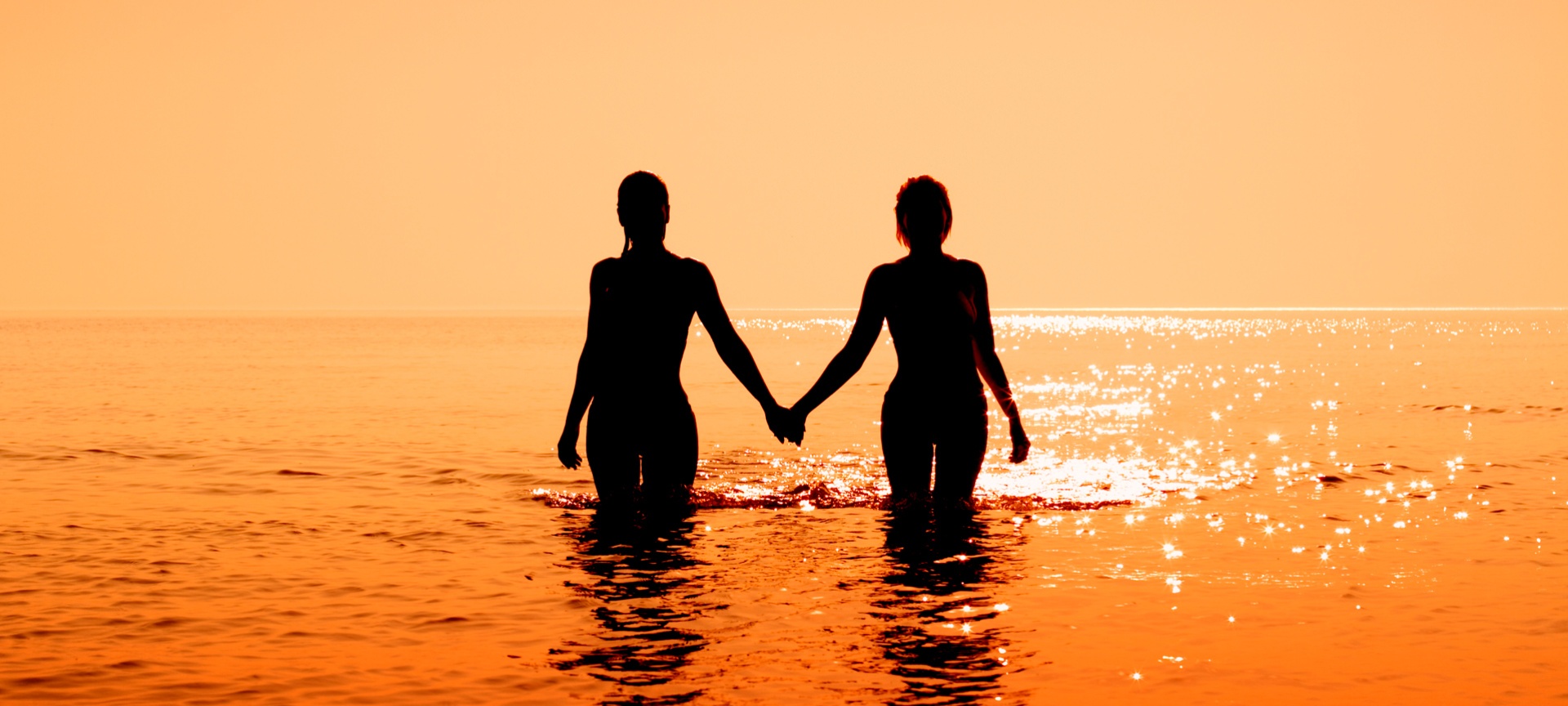 Coppia che entra in acqua al tramonto Coppia che entra in acqua al tramonto