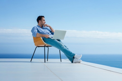  Uomo che lavora al pc con vista sul mare.