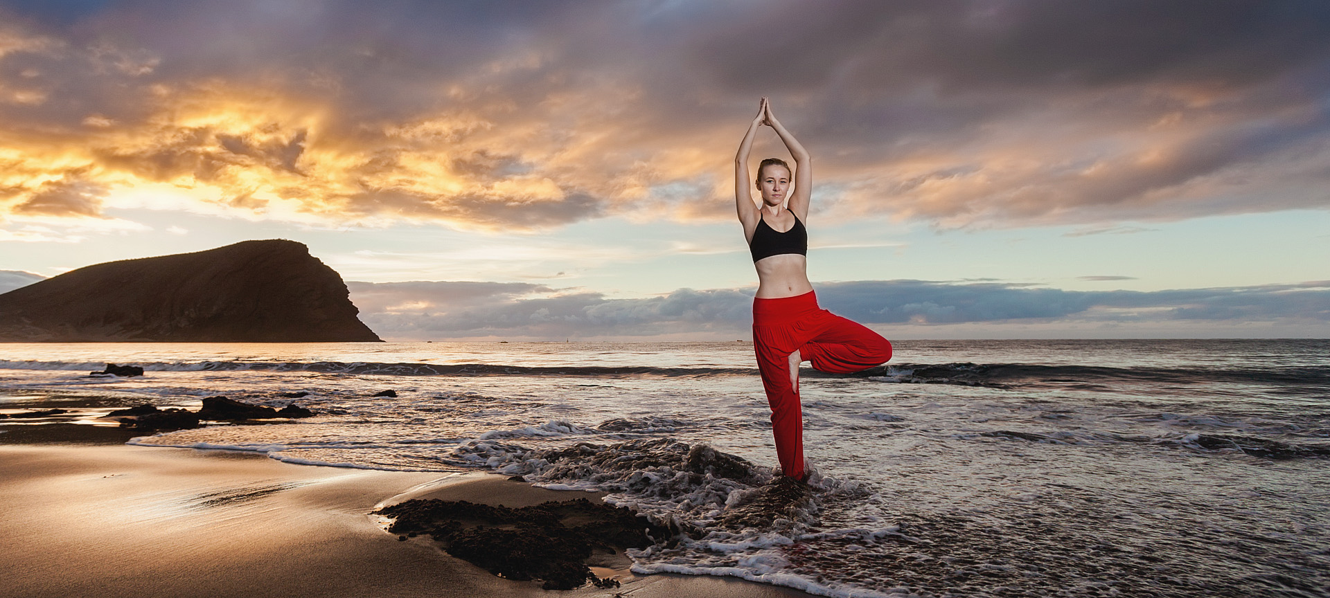 Una ragazza mentre fa yoga al tramonto sulla spiaggia di La Tejita di Granadilla de Abona a Tenerife, isole Canarie Una ragazza mentre fa yoga al tramonto sulla spiaggia di La Tejita di Granadilla de Abona a Tenerife, isole Canarie