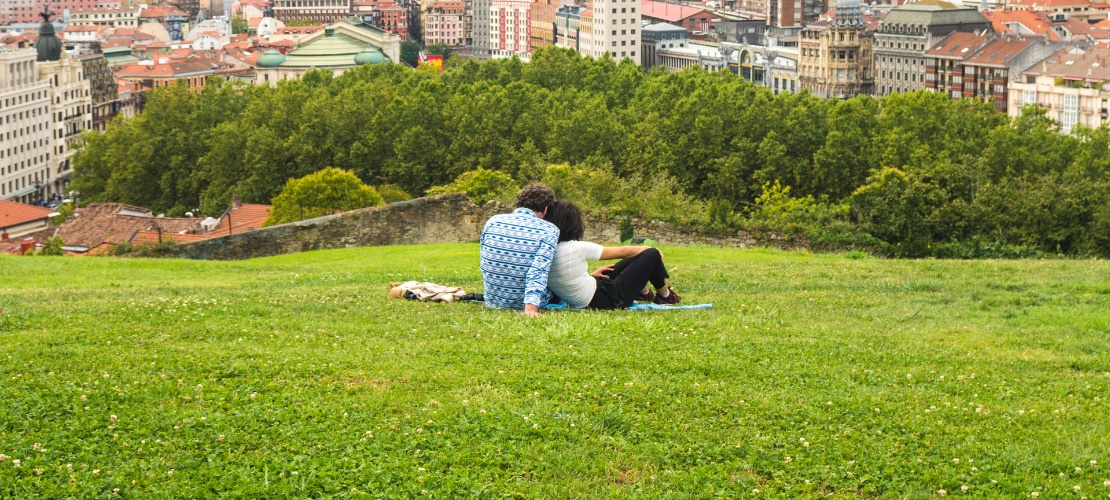 Pareja viendo una hermosa vista panorámica de Bilbao sentada en el parque de la colina sobre el Casco Antiguo
