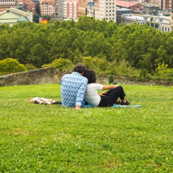 Pareja viendo una hermosa vista panorámica de Bilbao sentada en el parque de la colina sobre el Casco Antiguo