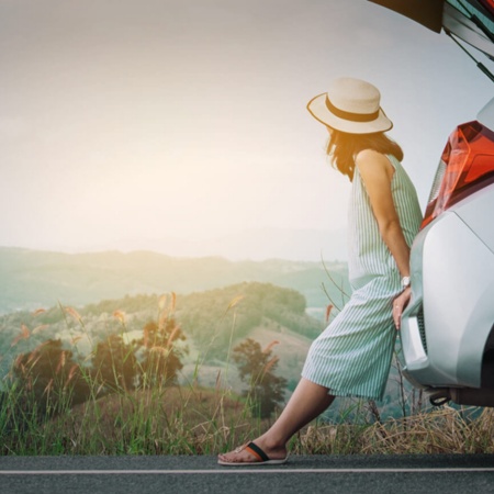 Turista appoggiata all'auto che si riposa durante il viaggio