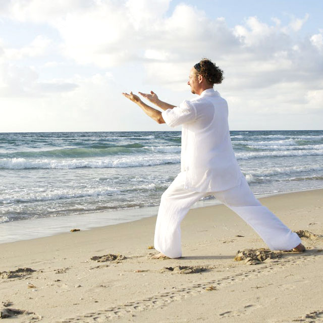Hombre practicando yoga en la playa Hombre practicando yoga en la playa